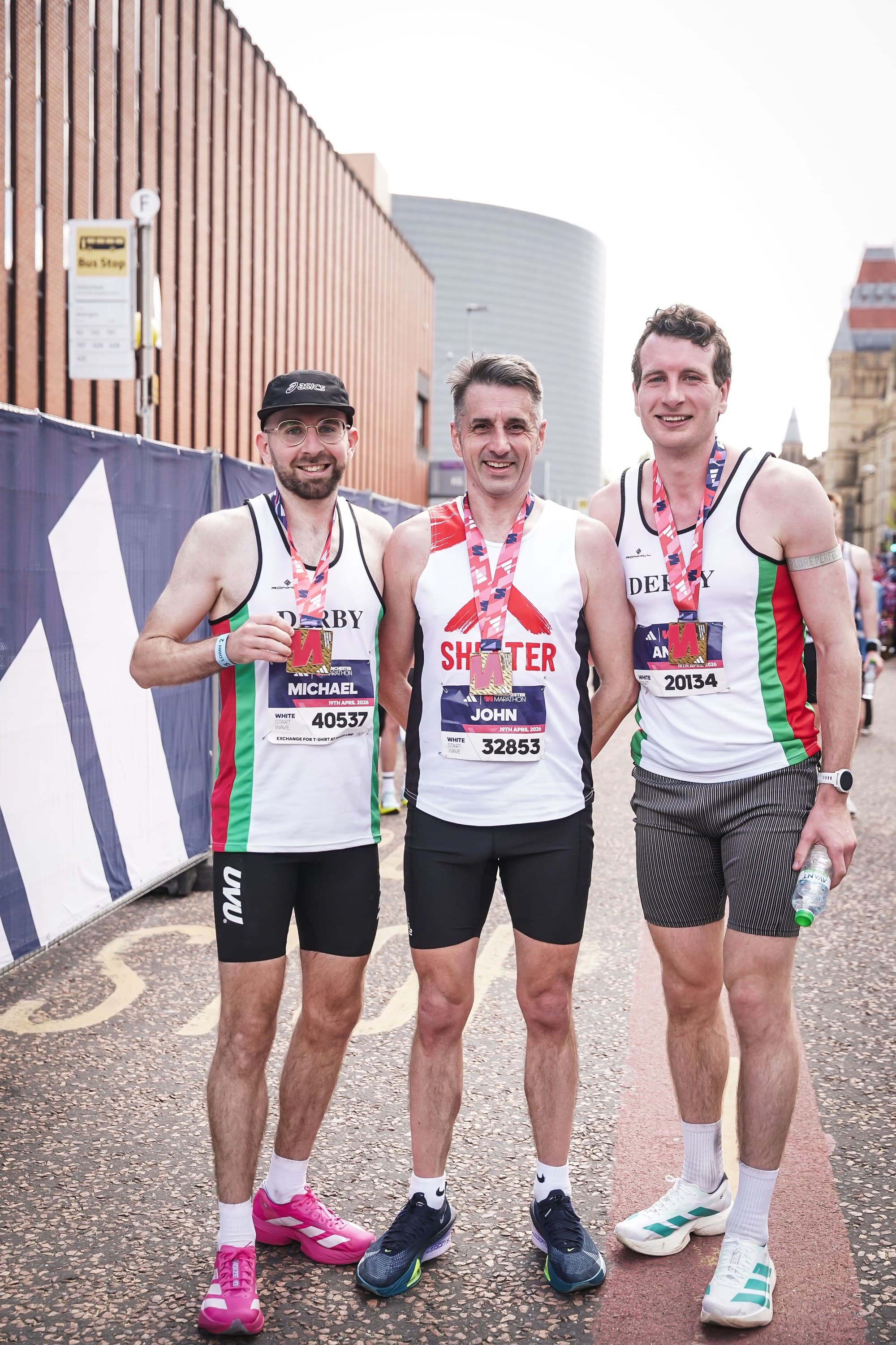 Three club runners in Derby Athletic Club vests with their medals after the Manchester Marathon